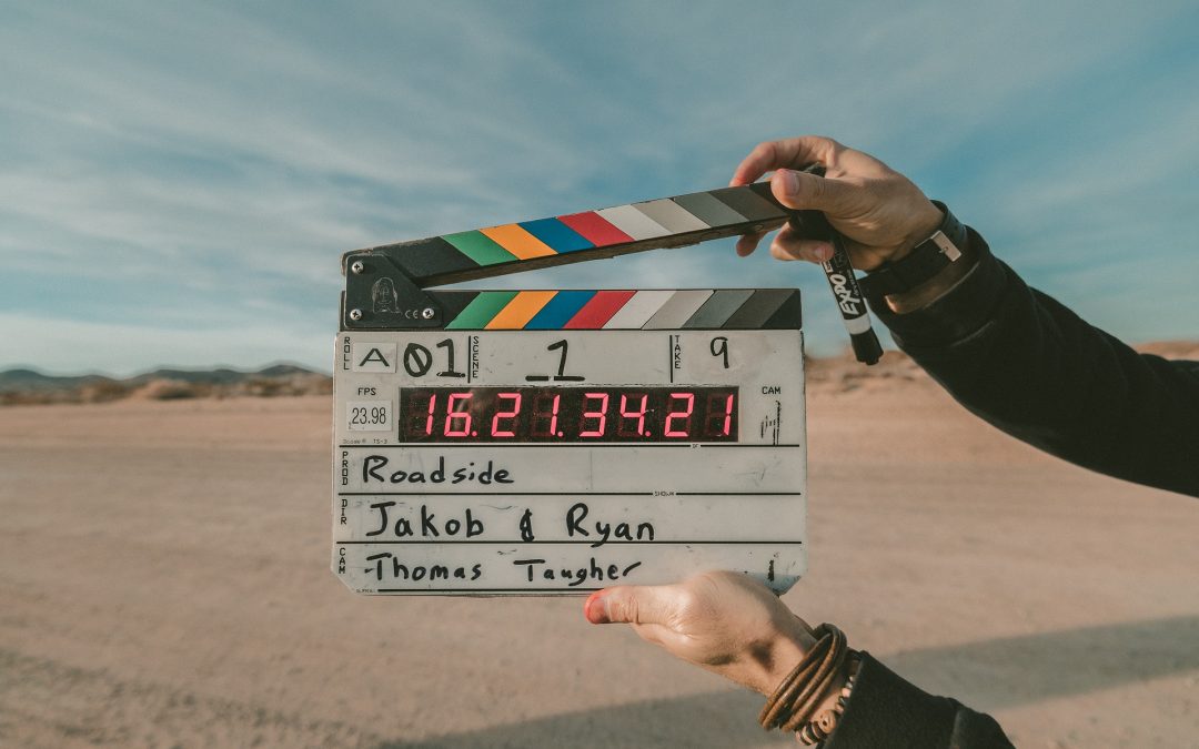Person holding a film clapper over a beach setting.