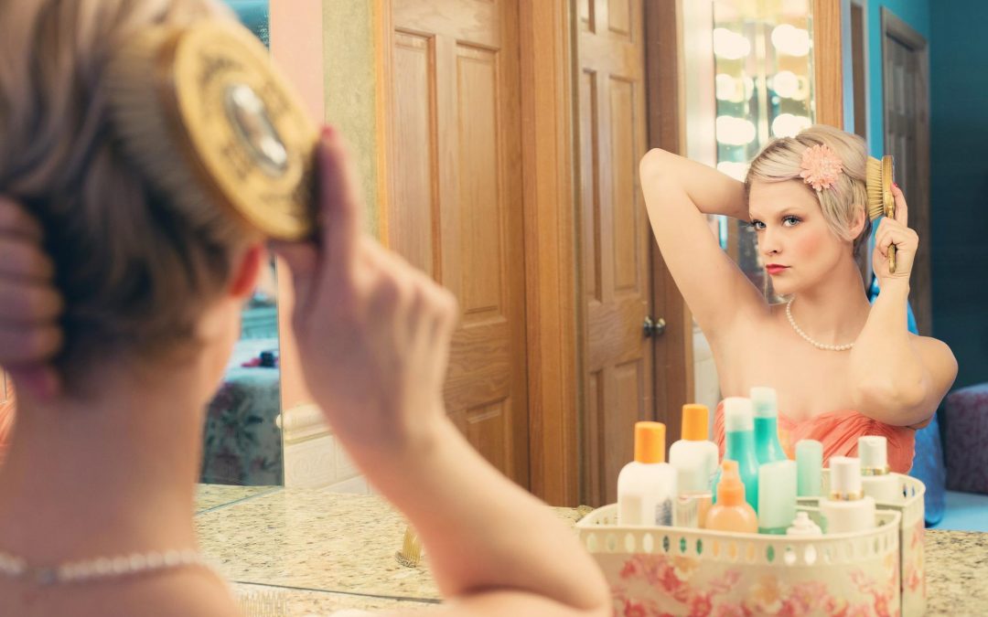 Woman looking in the mirror doing her hair.