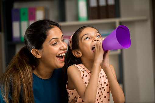 Woman and little girl speaking into paper megaphone