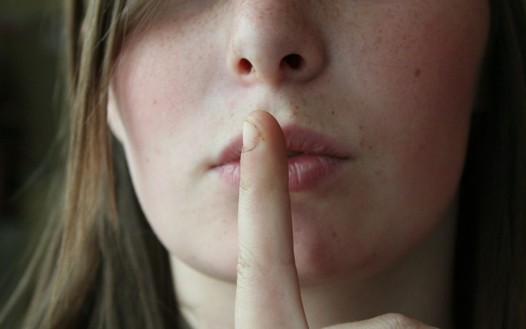 Girl with finger over lips 'shh-ing''