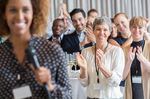 Group of people clapping, one person with a microphone