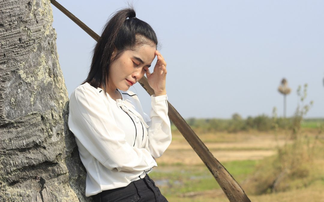 Woman leaning against tree crying