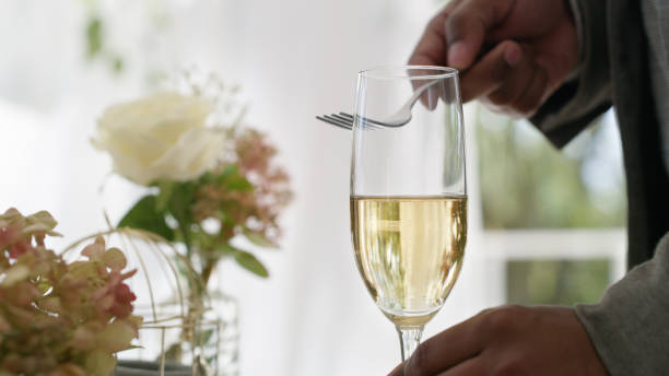 Shot of an unrecognizable man tapping a fork against a champagne glass to make an announcement